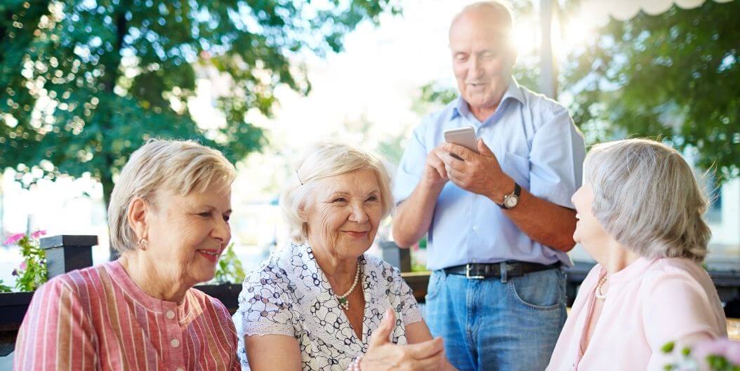 Group of Elderly Friends Laughing Together on Patio at Independent Living Facility