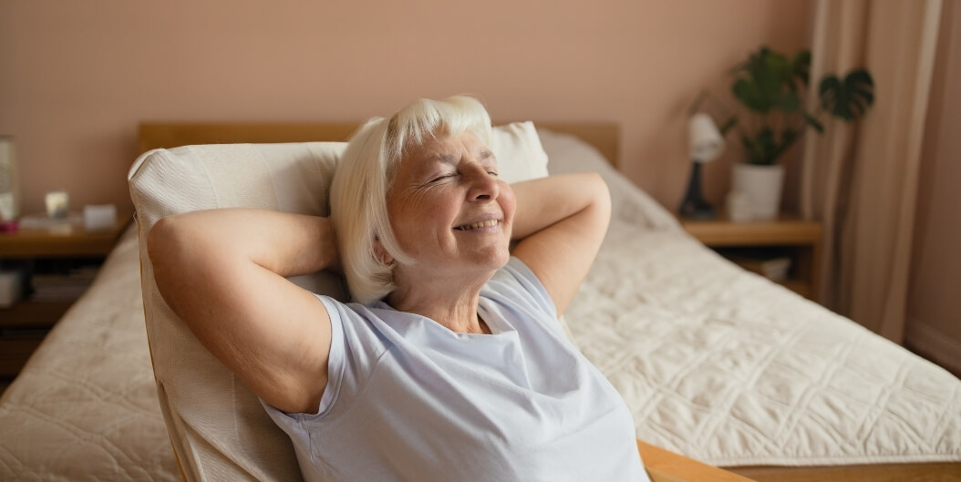 Senior Woman Relaxing in Apartment Bedroom at Independent Living Facility