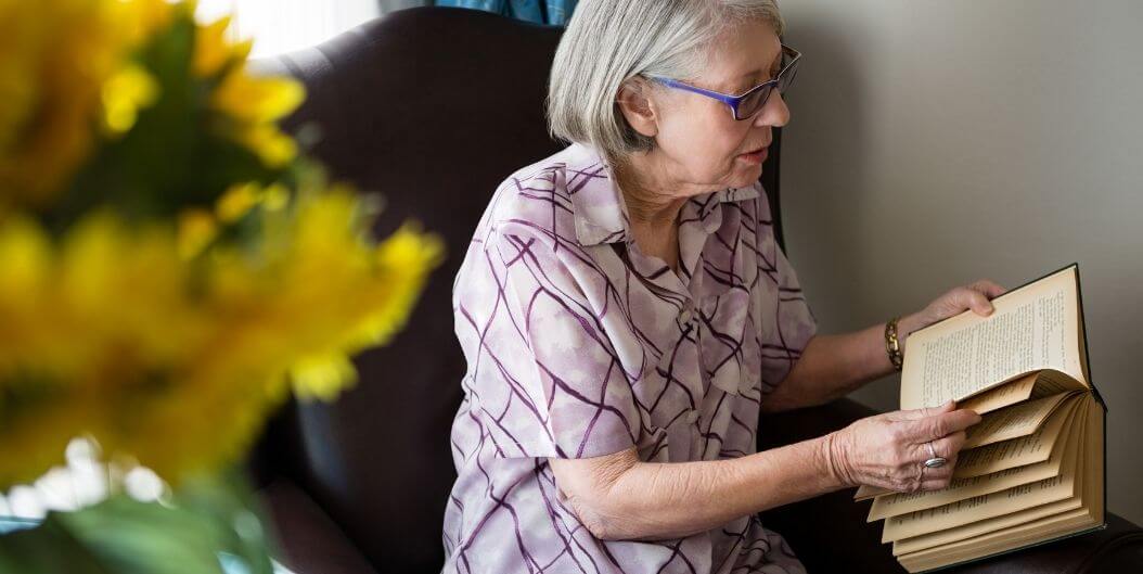 Elderly Woman Enjoying Print Book at Independent Living Facility