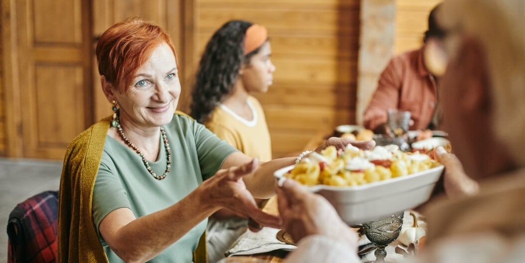 Elderly Woman Sharing a Cultural Pasta Dish at a Family Meal in Independent Living Facility