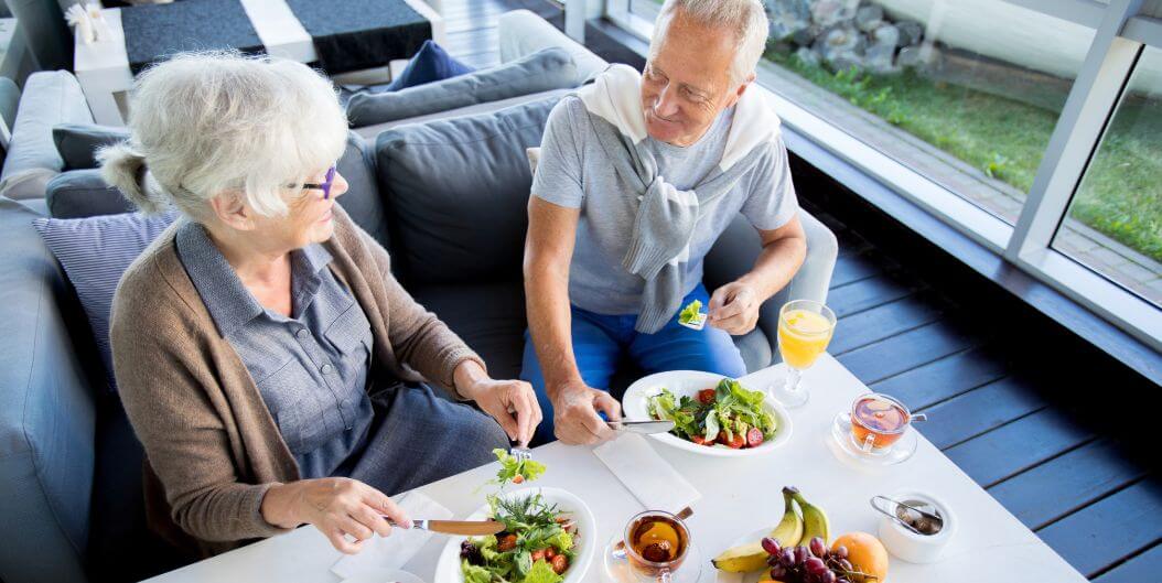 Elderly Couple Sharing Healthy Salad Lunch at Independent Facility